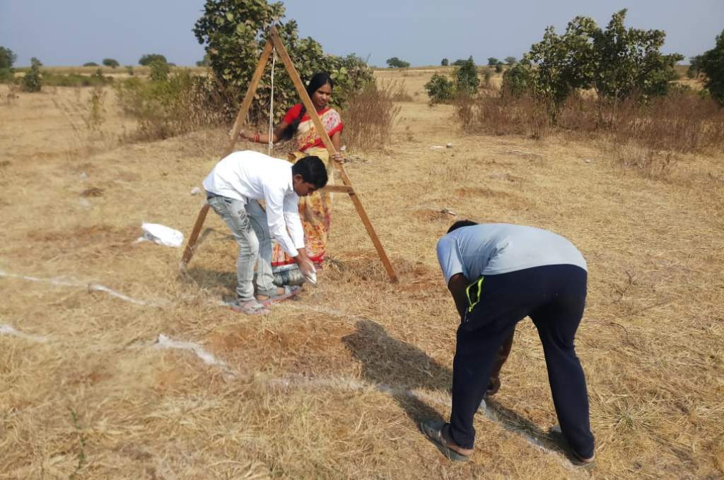 Two men drawing lines in a field with powder chalk while a woman observes them_sustainable agriculture