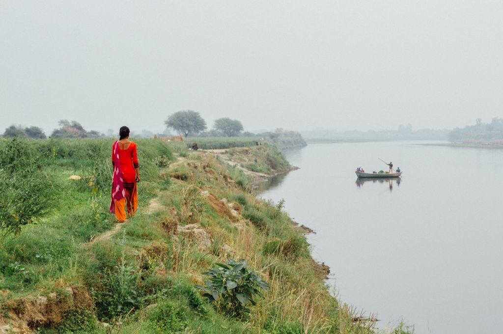 a woman farmer walking along a river-land rights