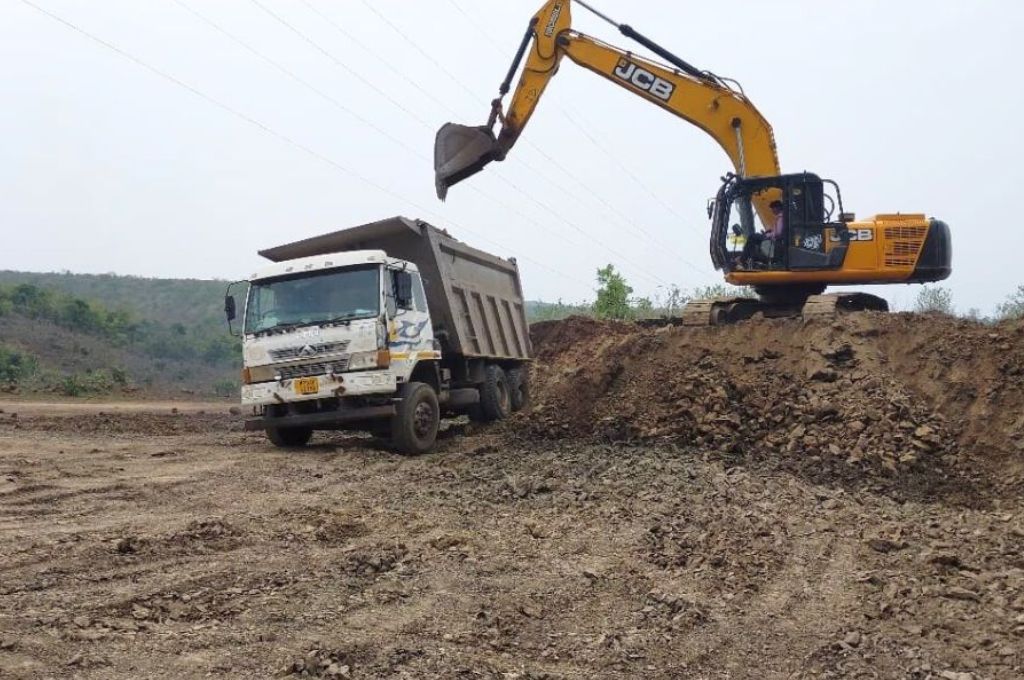 A JCB loading materials into a truck at a mining site--mining in Bhopal