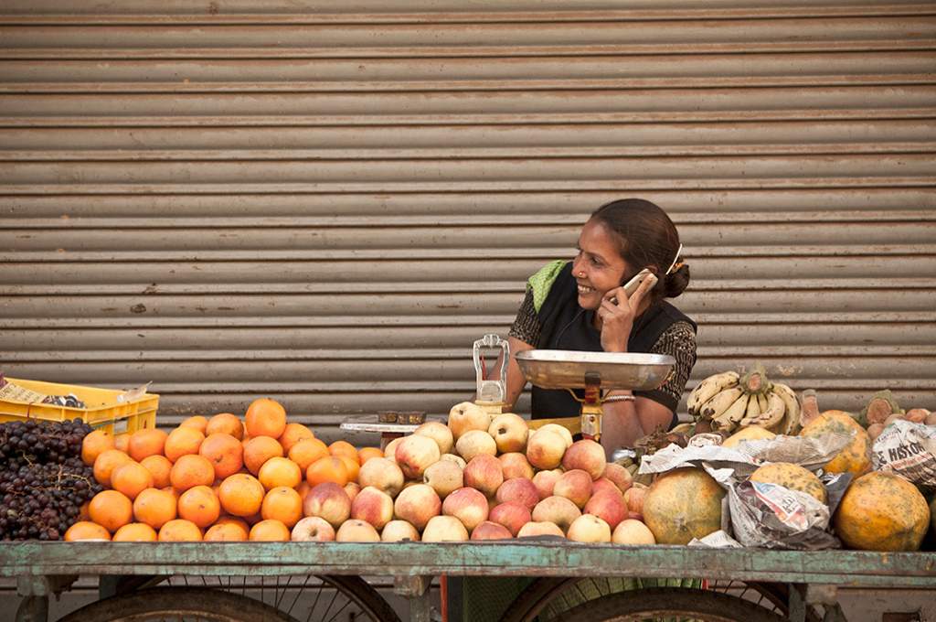 A woman with a vegetable cart, talking on the phone_financial inclusion