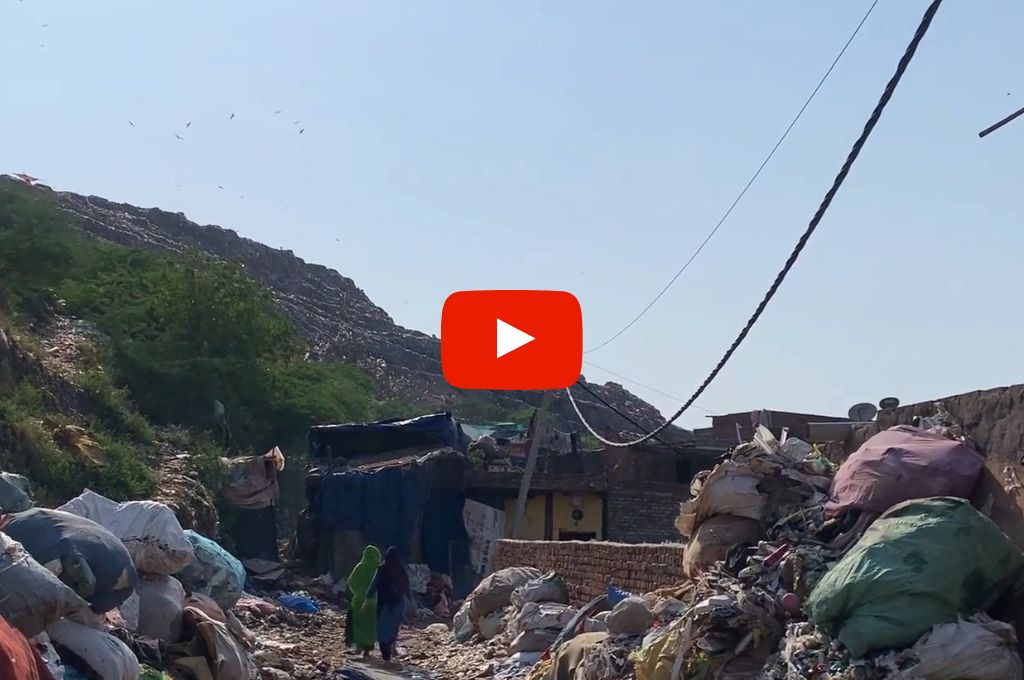 two women walking amidst piles of waste--waste workers