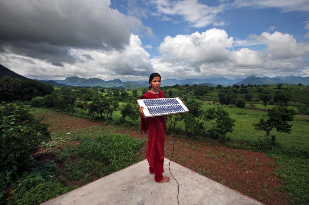 a woman holding a solar panel--clean energy transition