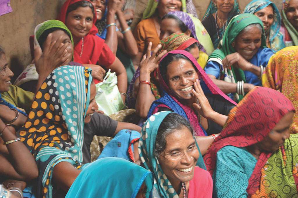 a group of women sitting on the floor, talking and smiling--women's land rights