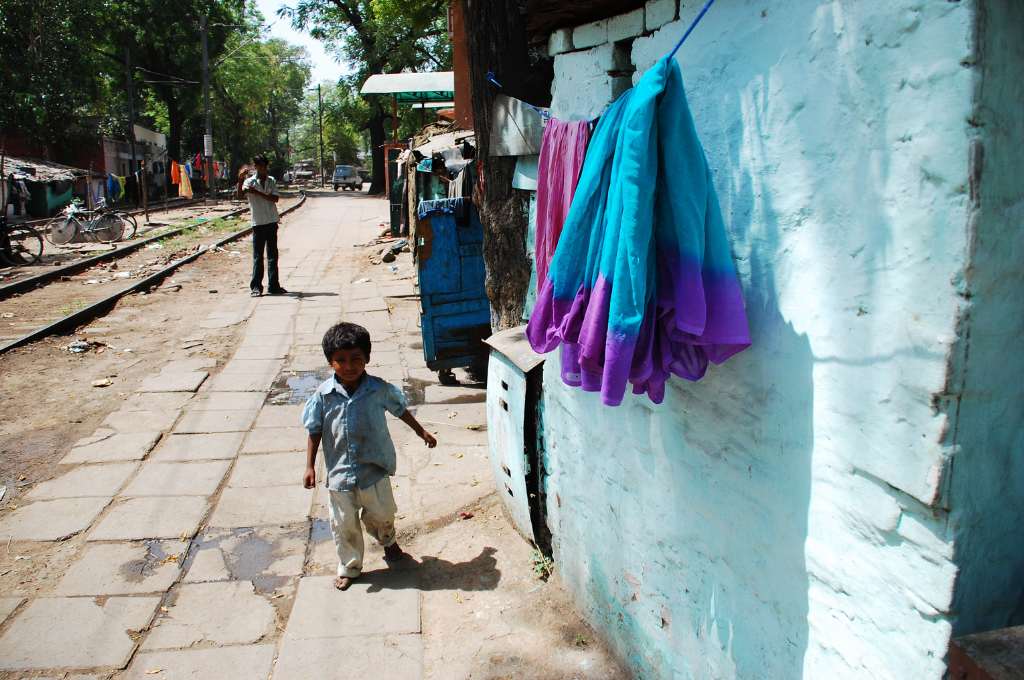 a young boy standing on a street next to railway tracks--leprosy in India
