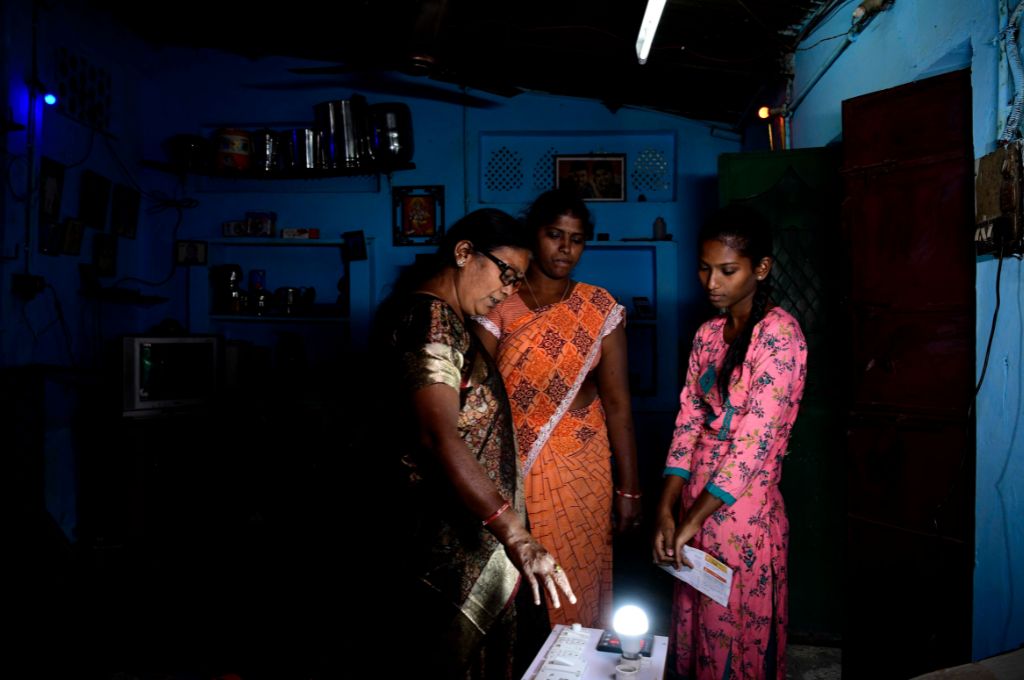 two women looking at a bulb--household electricity