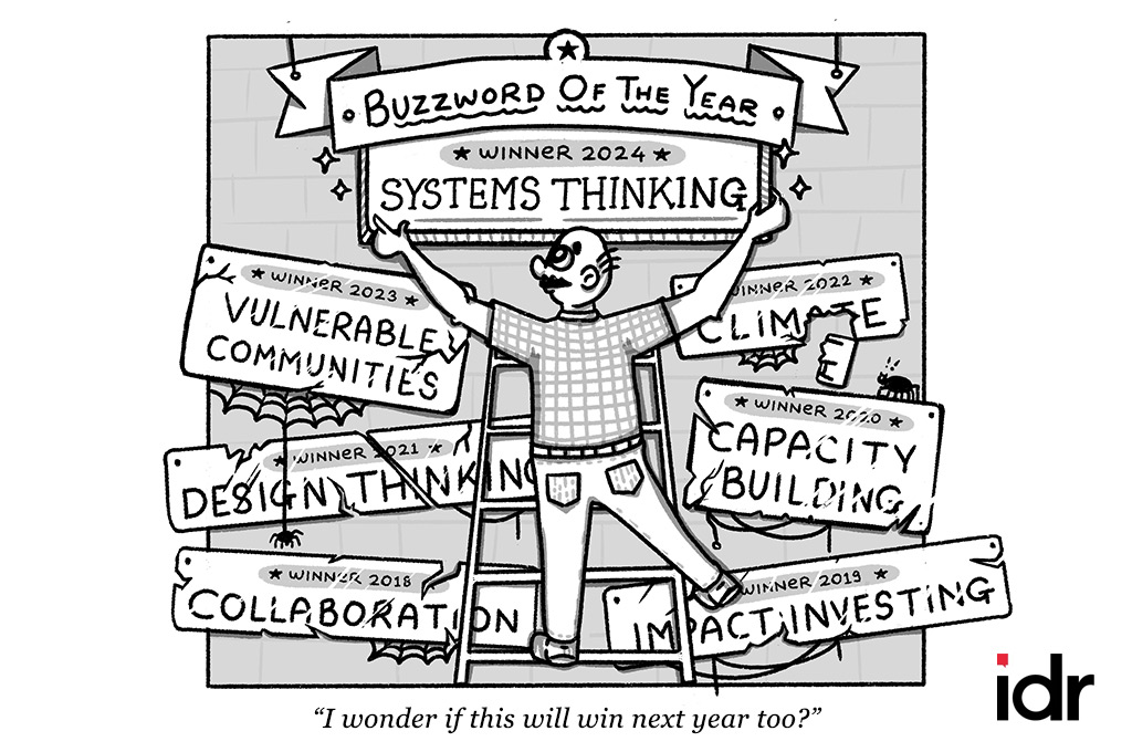 a man putting up a plaque saying that systems thinking is the buzzword of the year--nonprofit humour