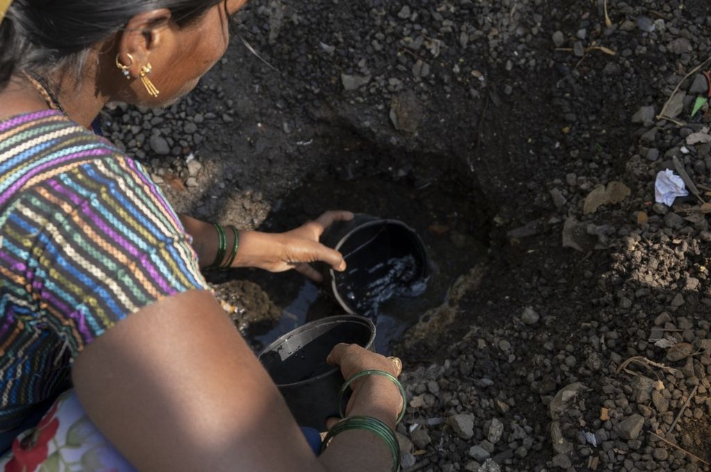a woman drawing water out of shallow pit_water rights