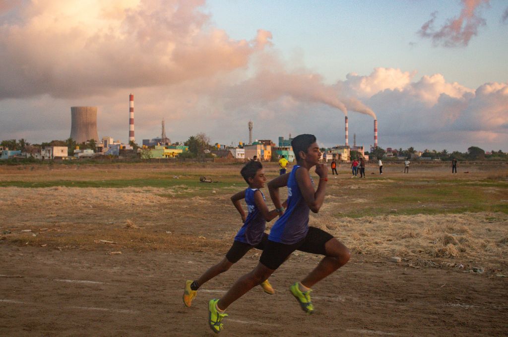 Two children running in football uniforms in the Burma ground. Players have breathing issues and low stamina because of the pollution_industrialisation