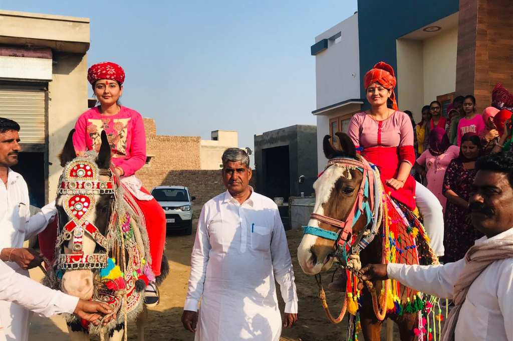 two brides sitting on two different horses with a man standing in the middle-dalit