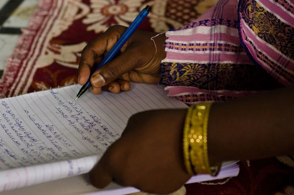 a close-up shot of a woman's hands as she writes something down in a notebook--fieldworkers