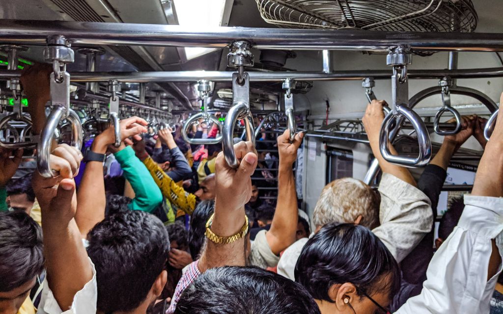 People standing in a crowded train with their hands taking support from grab handles_India's population growth