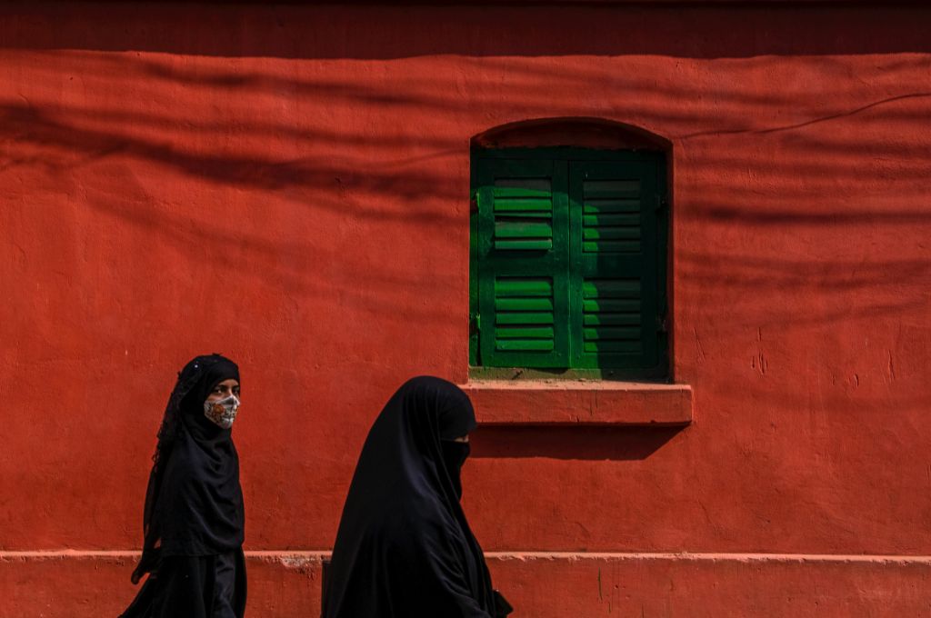 two burqa-clad women against a red background--Rohingya refugees in India