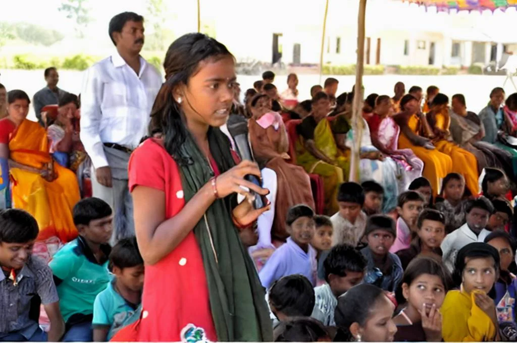 a girl speaking on a mic in a gram sabha-makkala gram sabhas