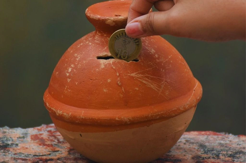 An image of someone putting a coin in a gullak_climate philanthropy