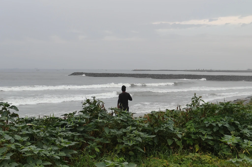 Man standing on a beach in a coastal city