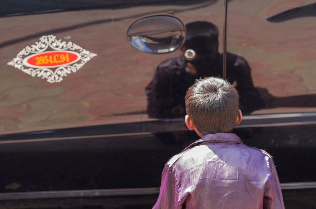 Child looking at a reflection of himself in a car_mental health