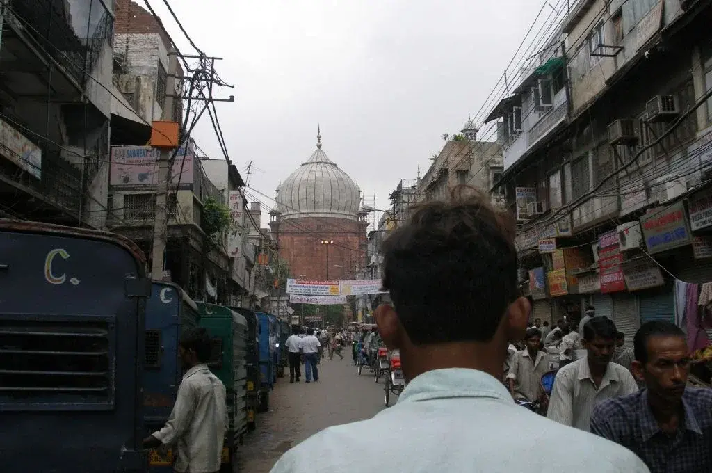 the back of a man's head in a busy road, looking at a mosque in the distance-transgender