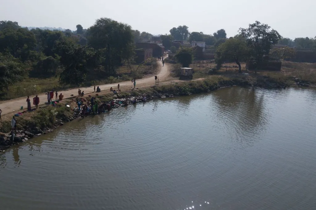 A few people gather at the edge of the tank in Alopa village which is filled with water - Water management