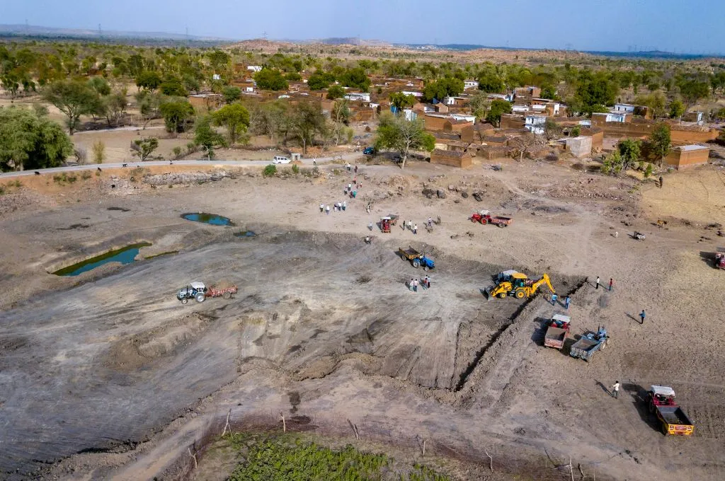 Bulldozers, trucks, and tractors are used at the site of the Alopa tank for desilting and restoration work. The tank is dry except for a few puddles of water - Water management