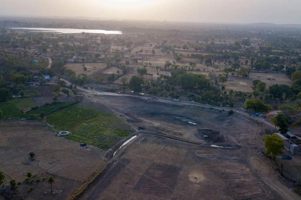 An aerial view of the tank in Mudara village before restoration. The tank site is dry except for a few puddles of water- Water management