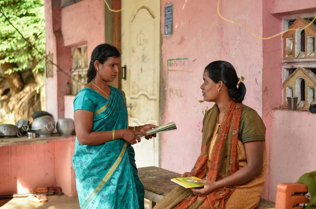 An ASHA worker holds a file in her hand and talks to a woman- Menopause in India