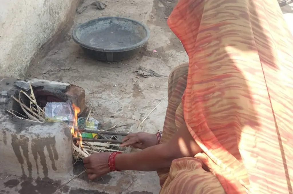 Woman using waste materials for outdoor cooking fire_waste management