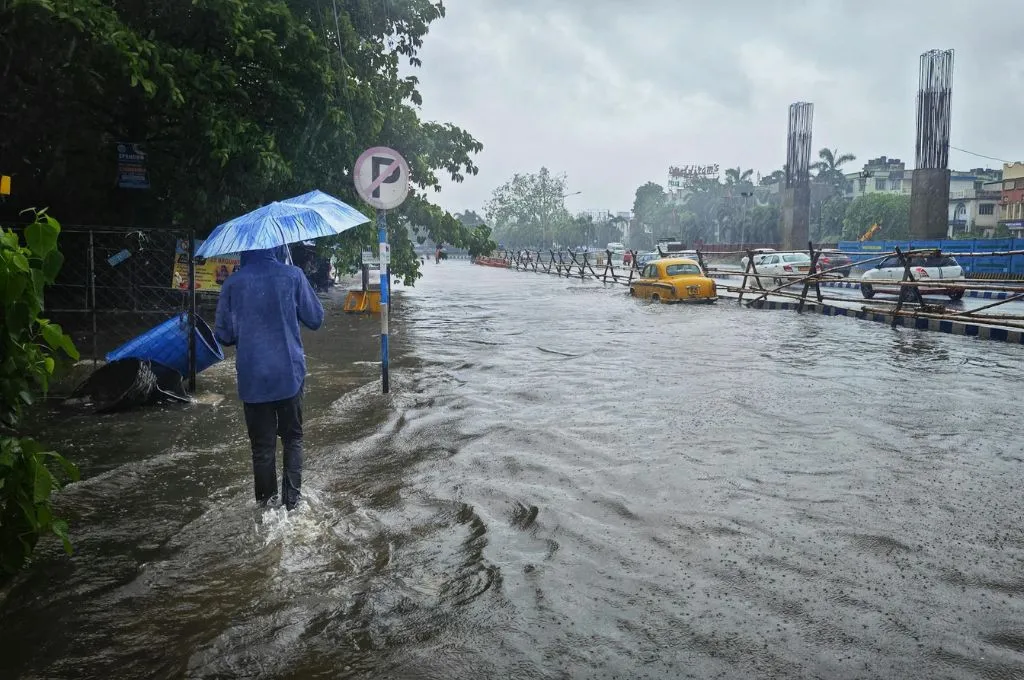 A person walking with an umbrella on a flooded street_climate crisis