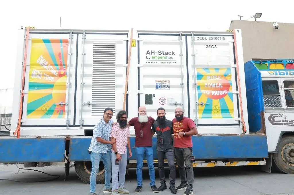 five band members standing in front of a renewable energy truck