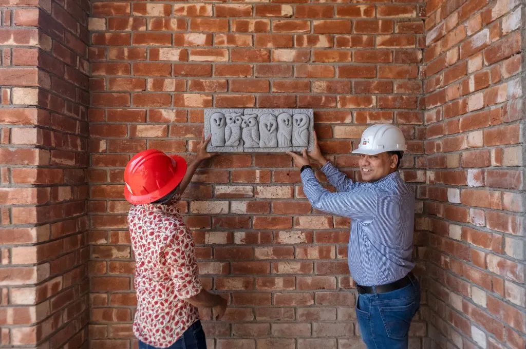 Two people holding up a plaque with owl designs on it-universal design