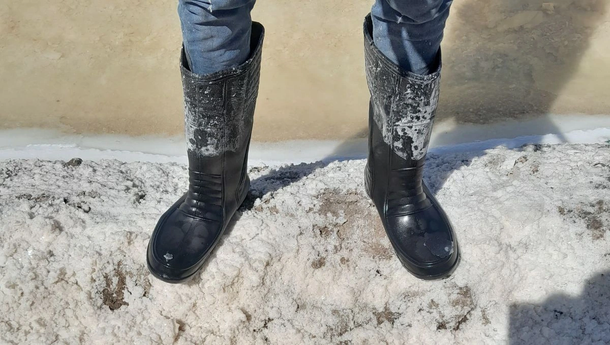 a close up shot of the boots being worn by a salt pan worker--salt farming