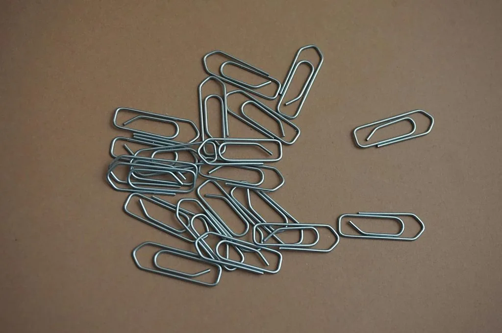 a bunch of about 50 paper clips lying on a brown surface-12A 80G