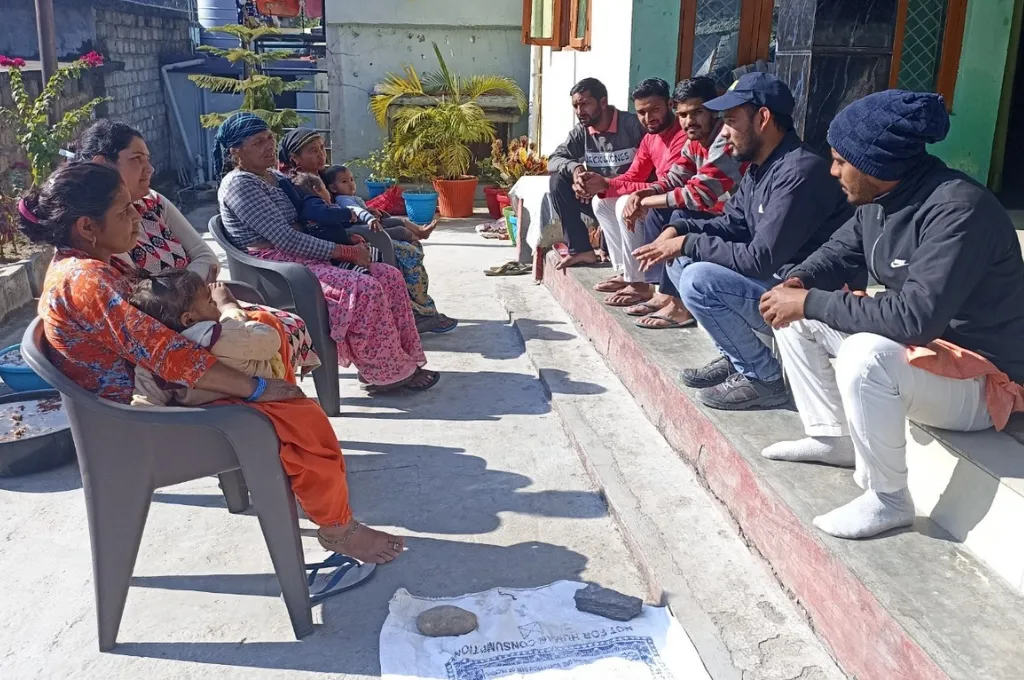a group of people sitting and talking on steps and a verandah outside on a sunny day--paryavaran sakhis