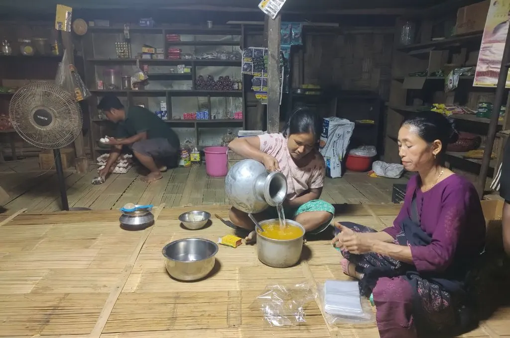 two women from the ronglang community sitting on the floor, which is covered with bamboo mats, and making ice pops.--bamboo-based livelihoods