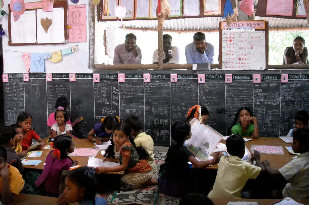 four adults--three males and a female--observing a class in session--teachers in india