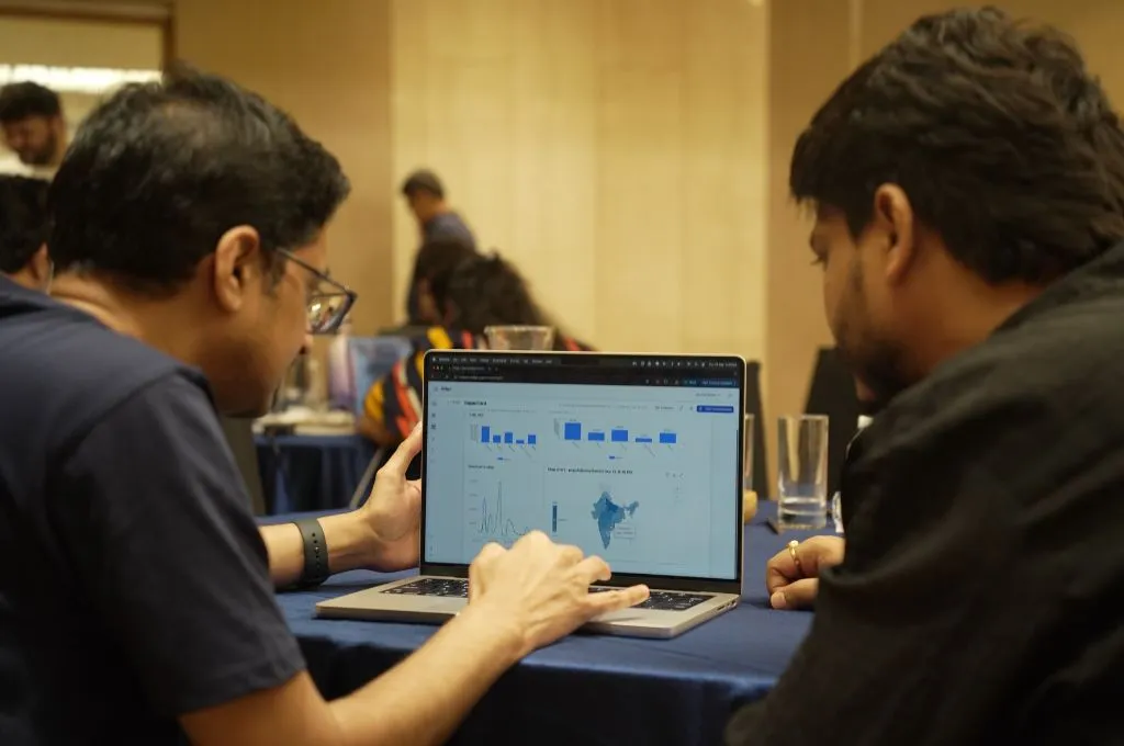two men looking at a line graph and a map of india on a laptop--nonprofit tech