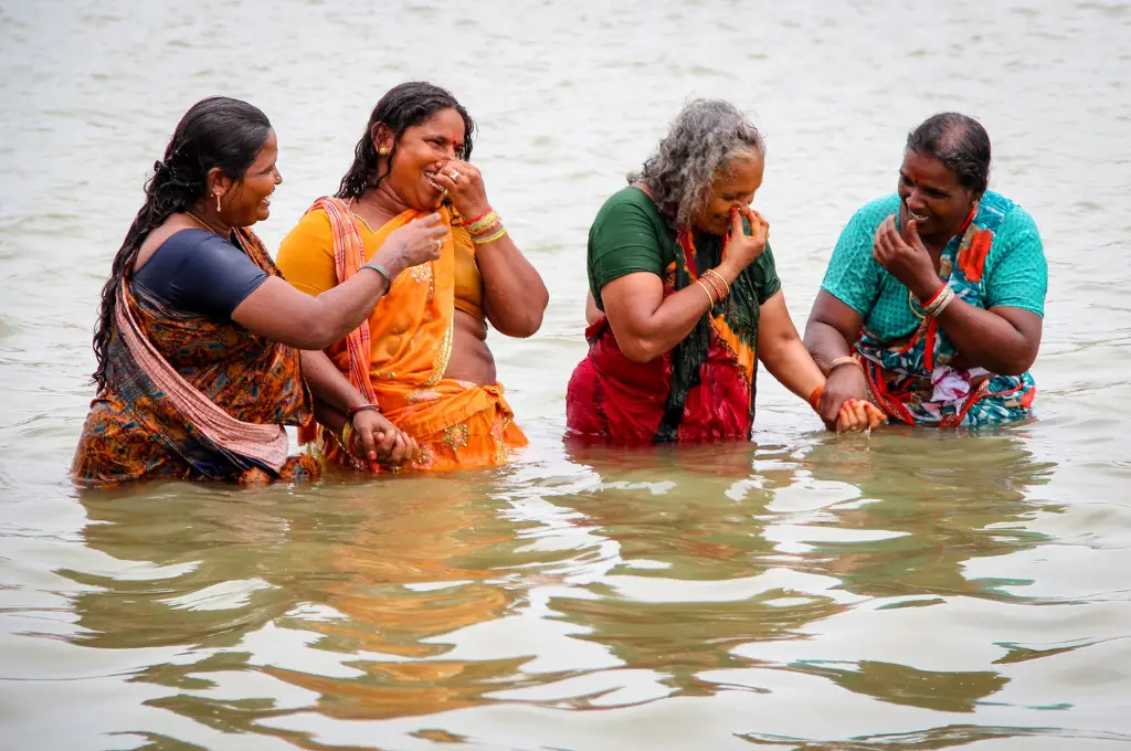 four women in sarees bathing in the river Ganga in Varanasi--elderly care