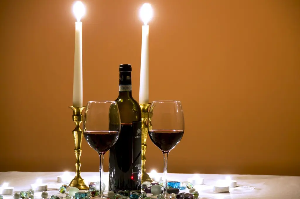 two wine glasses, a bottle of wine, and two lit candles on a table--nonprofit humour