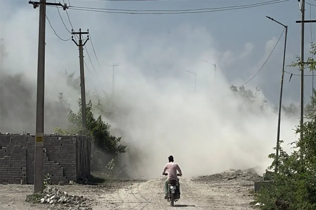 A person on a bike riding through fly ash on a dusty road