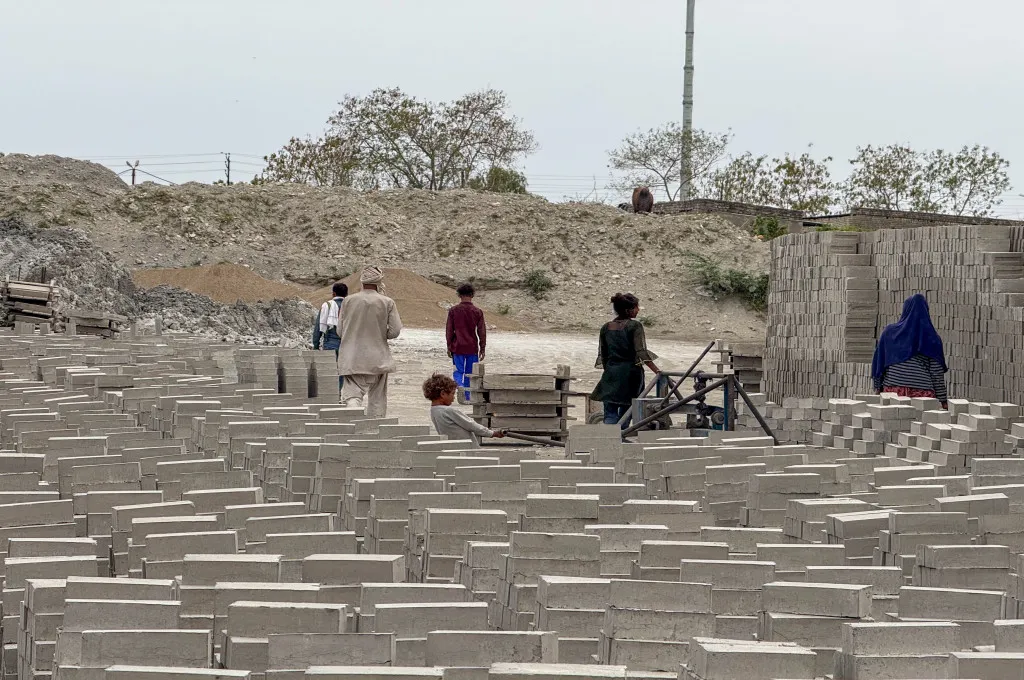workers at a fly ash unit with their children, with fly ash bricks everywhere--fly ash