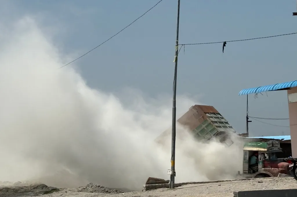 a truck unloading fly ash with much of it being blown in the air--fly ash