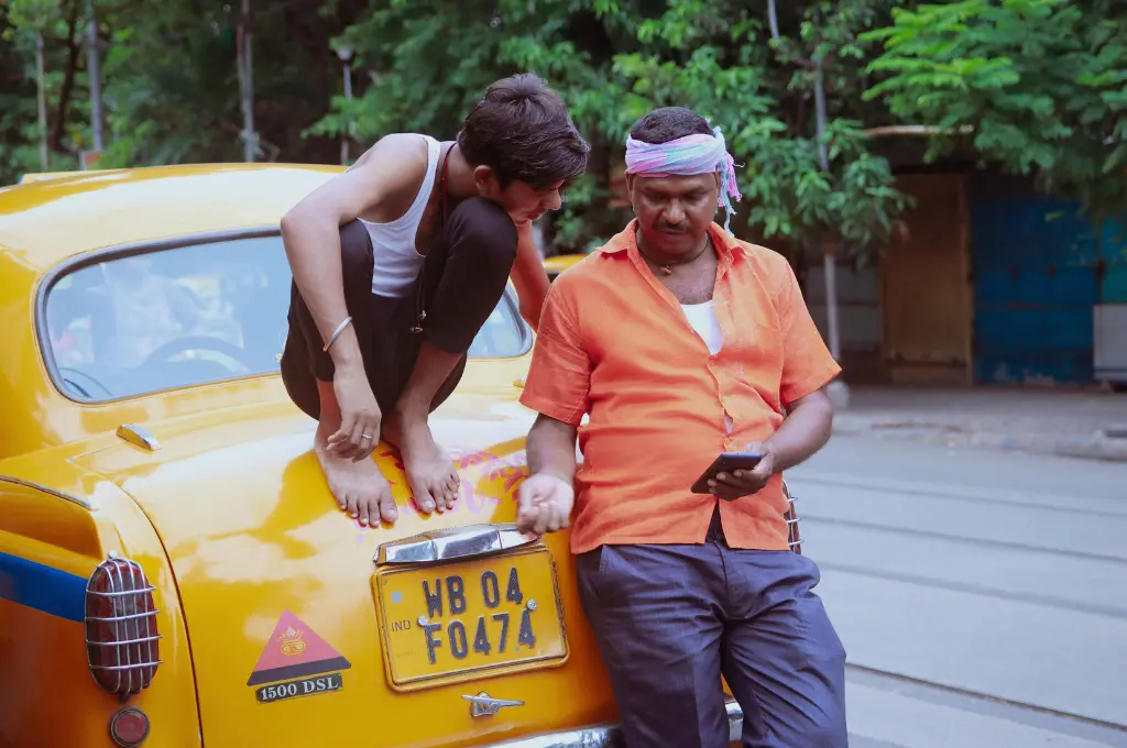 two men leaning on a yellow taxi, one sitting on the trunk and the other holding a smartphone--misinformation