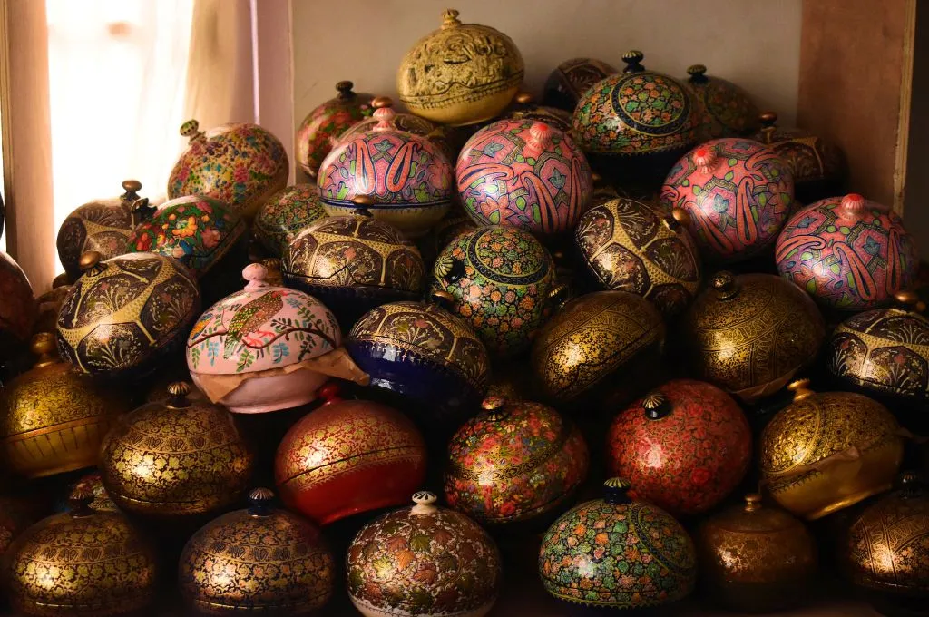 A pile of painted paper-mache Christmas ornaments, each featuring different colours and intricate designs.--paper-mache in Kashmir