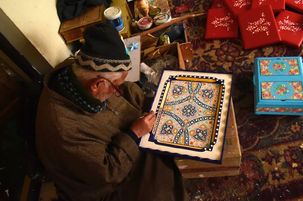 a paper-mache artisan painting a frame--paper-mache in Kashmir