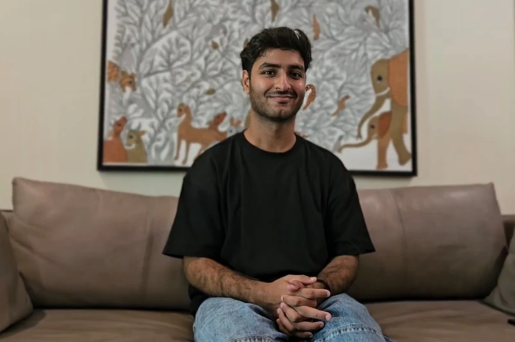 A picture of Parmeet in black t-shirt and blue jeans, sitting on a couch--deaf community