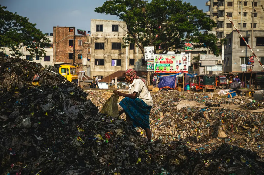 a person collecting trash from a pile of garbage--sanitation workers