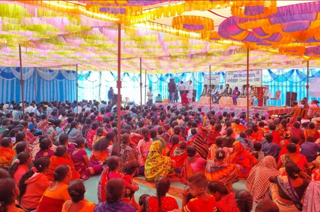 a large crowd gathered for a rally sitting on the floor under tents--rights and development