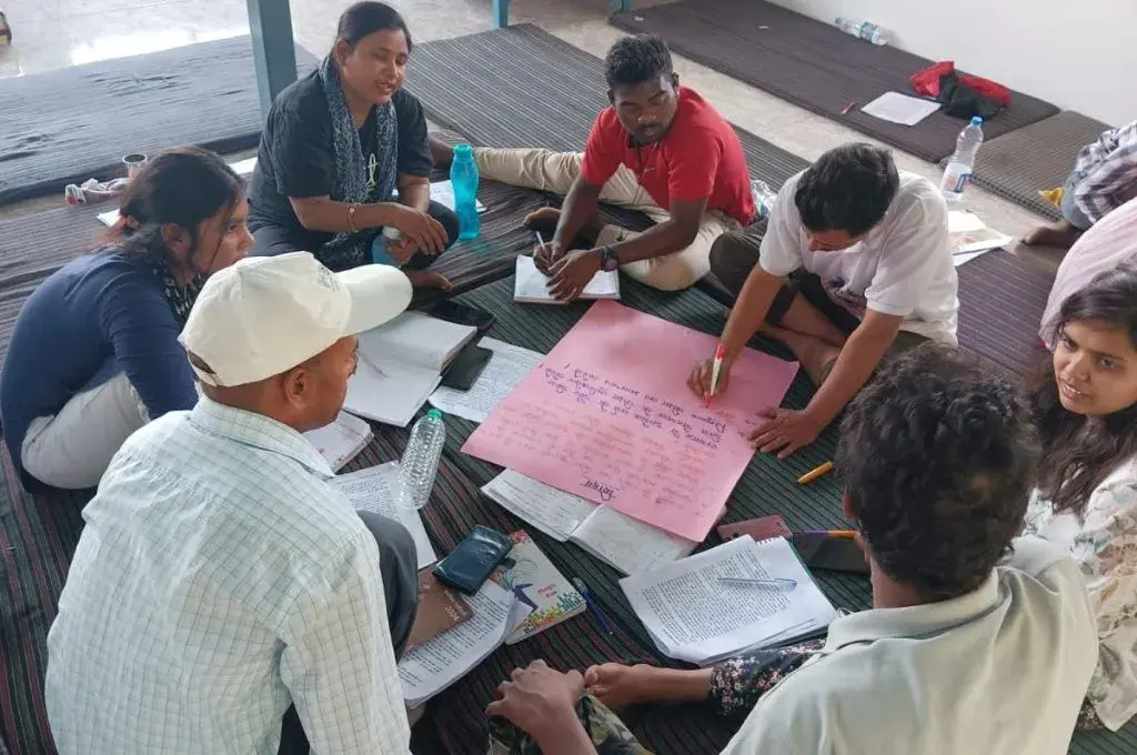 a group of people sitting in a circle with notebooks and posters--leadership development programmes