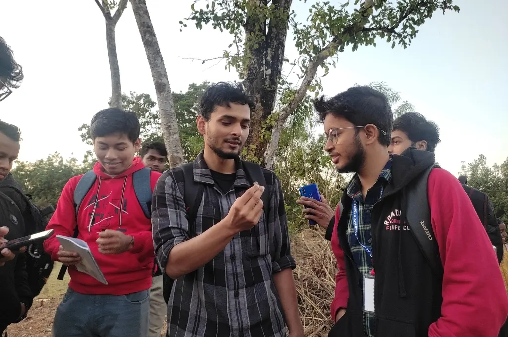 Hansatanu Roy holding up a wood fungus and showing it to a group of students--citizen science