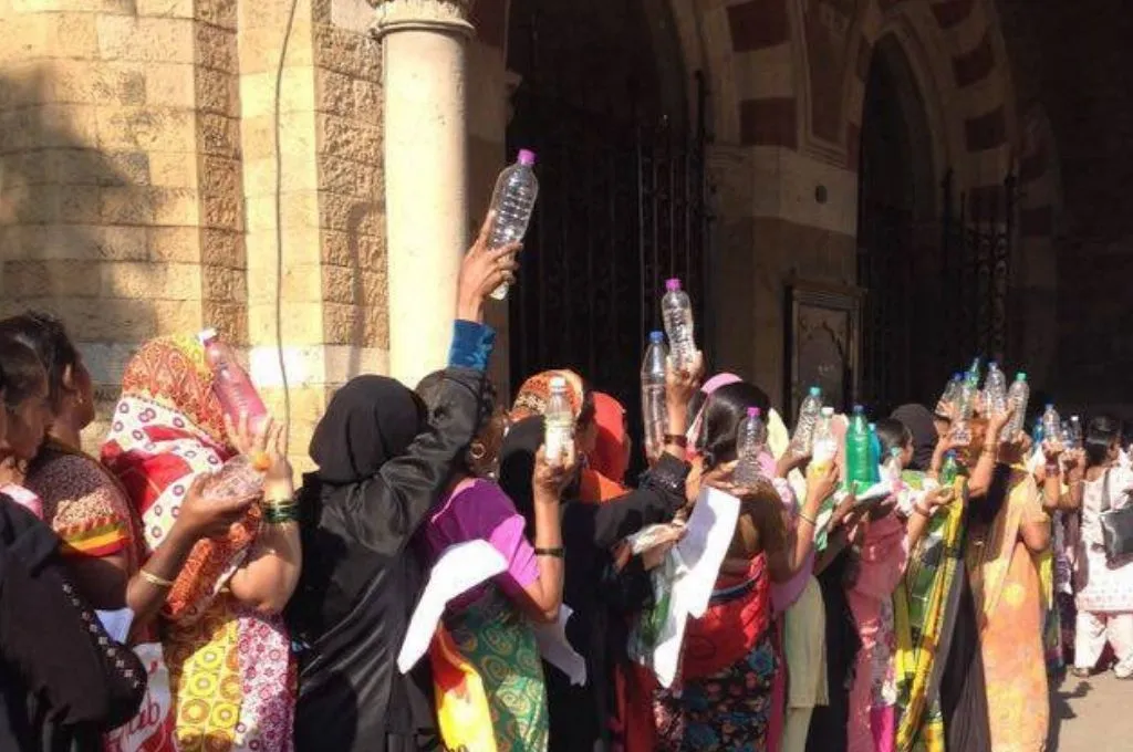 a crowd of women holding up plastic water bottles with their backs to the camera--social movements