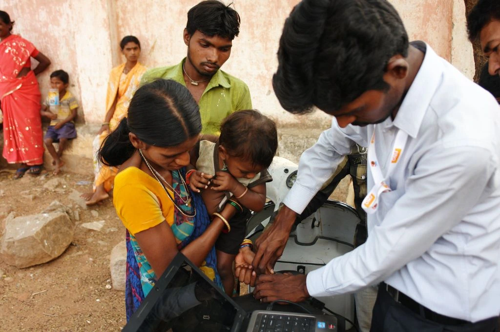 A woman carrying an infant for the infant's biometrics to be captured for a government scheme in Andhra Pradesh--grievance redressal mechanisms